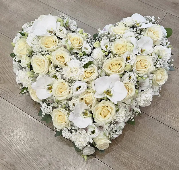 Cœur de roses blanches et de fleurs délicates composé pour un hommage