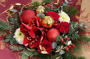 Composition de Noël aux amaryllis rouges, boules dorées et branches de sapin