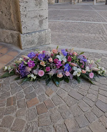 Composition allongée de fleurs mauves et blanches pour un dessus de cercueil