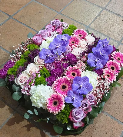 Coussin de fleurs violettes, roses et blanches