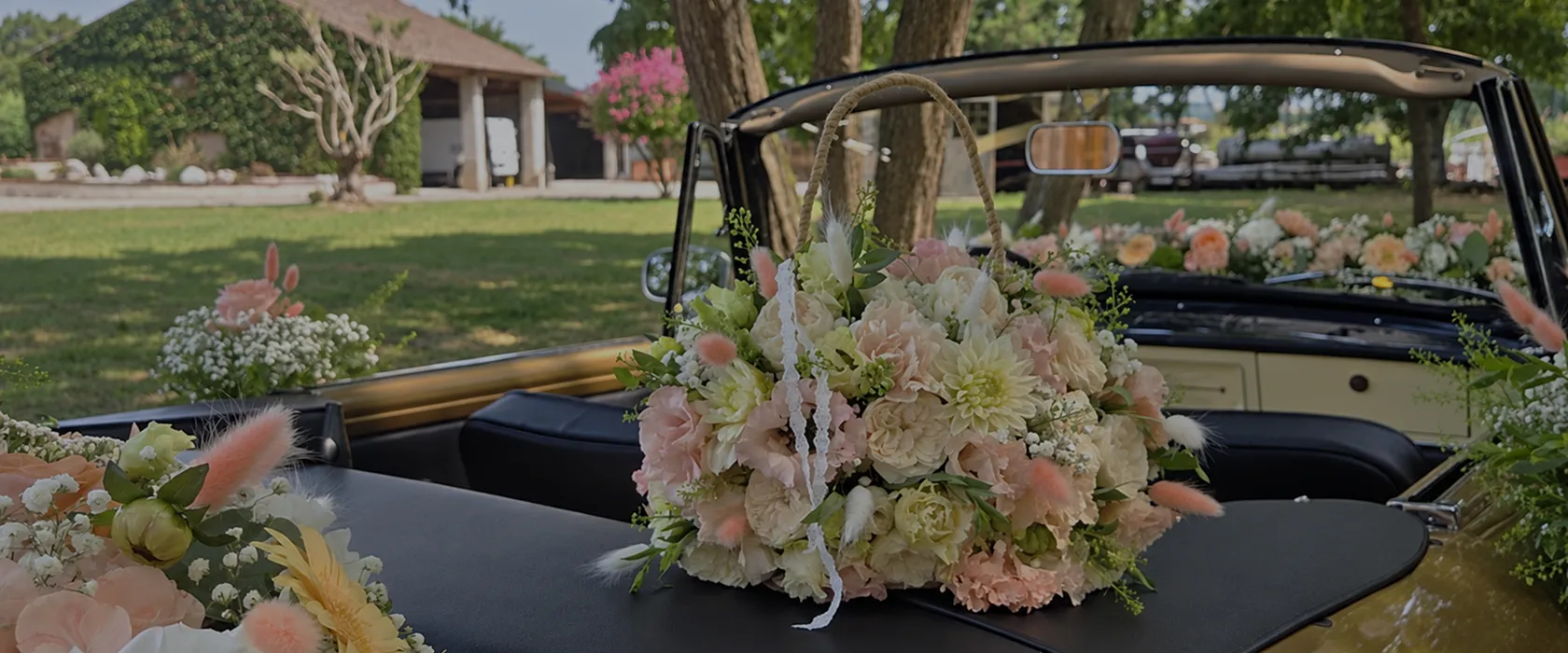 Bouquet de mariage blanc et rose posé sur une voiture ancienne décapotable