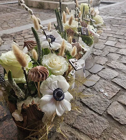 Composition de roses blanches et d’anémones posée sur des pavés