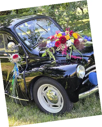 Voiture ancienne noire décorée d’un bouquet coloré sur le capot pour un mariage