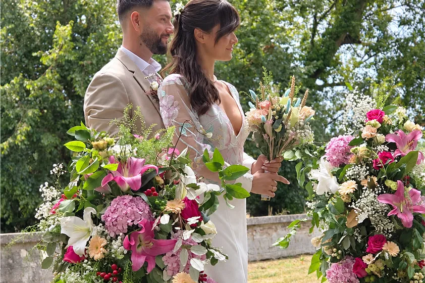 Jeunes mariés entourés de compositions florales colorées, en extérieur