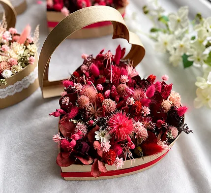 Boîte en forme de cœur garnie de fleurs séchées rouges et roses