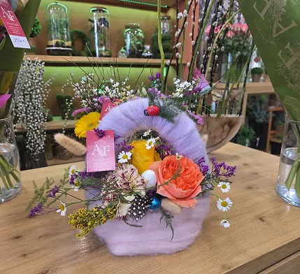 Composition florale dans un panier lilas, réalisée en atelier sur l’établi de la boutique