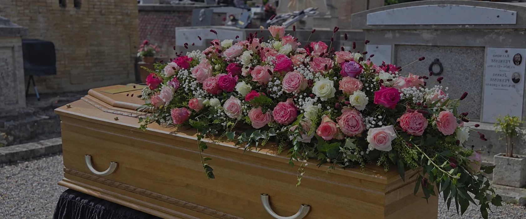 Dessus de cercueil fleuri de roses roses et blanches lors d’une cérémonie funéraire