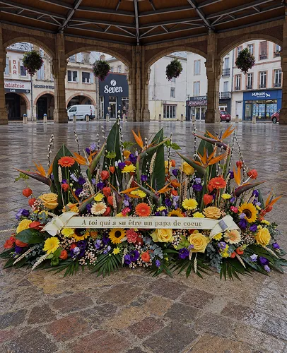 Composition funéraire fleurie accompagnée d’une plaque d’hommage